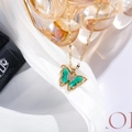 Macro shot of gold butterfly necklace with green wings and zircons on white silk - Peacock Green