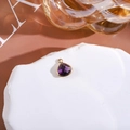 Macro detail of a purple teardrop crystal pendant with a polished gold metal frame finish - Violet