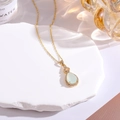 Macro shot of gold plated teardrop pendant with pale green stone and zircon inlay - Synthetic Light Green Jade