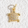 Dettaglio di un ciondolo a tartaruga dorata con strass bianchi su sfondo testurizzato - Ciondolo a Tartaruga con Guscio in Pavé di Strass (DYL-4660)
