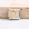 Macro shot of gold letter D on polished stainless steel Italian modular charm link - Letter D