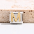 Macro detail of Italian charm bracelet link with gold polished letter M on steel - Letter M