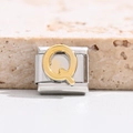 Macro detail of Italian charm link featuring a golden relief letter Q on stainless steel - Letter Q