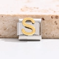 Macro shot of Italian charm link featuring a gold relief letter S on polished steel - Letter S