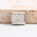 Makrofoto eines silbernen Edelstahl-Armbandglieds mit einem polierten Buchstaben X - Buchstabe X