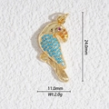 Détail d'un pendentif perroquet doré avec des perles bleues et des pierres rouges sur pierre - Perroquet avec Accents Bleus (DZ-3219)