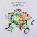 Macro shot of 1.2x8x3mm spike eyebrow rings with colorful splatter paint patterns - Curved Spike Eyebrow Ring (JE0099C) / 10 Pieces Pack / Multicolor