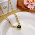 Dettaglio di una collana a catena serpente dorata con ciondolo a cuore in cristallo verde - Collana Cuore Zirconia Verde (86497)