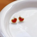 Détail de boucles d'oreilles cœur rouge plaqué or sur un plateau en céramique blanc - Boucles d'oreilles clous cœur émaillé rouge (789) / Or