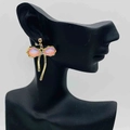 Golden bow earrings with pink cat eye stone and asymmetrical tassel on model - Gold Pink Cat Eye Bowknot Tassel Earrings (JE0916D)