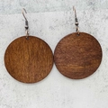 Detailed close-up of walnut wood disc earrings with bronze hooks on a stone surface - Smooth Wood Disk Style (JE1542I)