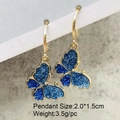 Gold butterfly earrings with sparkling blue glitter wings and metallic pendant details - Dark Blue Glitter Butterfly Style (JE1549E)
