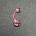 Close-up of pink acrylic navel ring with colorful sequins on a dark textured background - Transparent Pink Sequin Belly Ring (JE1597H)