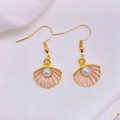 Detail of pink shell earrings with gold edges and a white pearl on white fabric - Pink Shell With Artificial Pearl (JE1614Q)