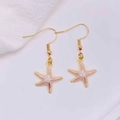 Close-up of golden starfish earrings with pink and white enamel on a soft background - Pink And White Enamel Starfish (JE1614N)