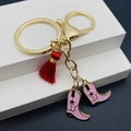 Detailansicht von rosa Cowboystiefel-Anhänger und roter Quaste an Gold-Schlüsselanhänger - Rosa Stiefelstil (B)