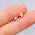 Pair of gold and silver snowflake labret studs with zircon inlays held between fingers - Snowflake Shape (JE1653E)