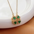 Collana a quadrifoglio dorata con pietre a cuore verdi e cristalli su sfondo di seta - Quadrifoglio Cuore Ciano