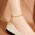 Elegantes goldenes Kugel-Fußkettchen am Knöchel mit Satinschuhen auf Seidenhintergrund - Goldener Rundperlenstil