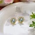 Pendientes vintage dorados con esmalte azul claro y perlas en un plato de cerámica - Estilo de Patrón Vintage de Esmalte Azul Claro