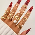Dettaglio di un set di anelli dorati con perle e farfalle indossati su una mano femminile - Stile Oro (HS1546-32) / Set da 20