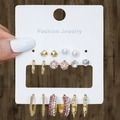 9-piece golden earring set with faux pearls, crystals, and hoops on a display card - 9 Styles Gold Colorful Rhinestone Collection (HS1589-7)