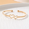 Golden open cuff bracelet featuring interconnected hollow heart shapes and smooth bead ends - Double Heart Hollow Bead Style (HS1974-14)