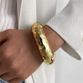 Modern irregular hammered gold cuff bracelet with textured ripple surface on female model - Concave-Convex Round Bracelet / Gold