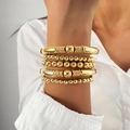 Gros plan d'un ensemble de cinq bracelets dorés à perles portés par un mannequin - Bracelets Empilables Or (HS1743-1)