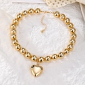 Collar punk de grandes cuentas doradas con colgante de corazón sobre fondo de encaje - Estilo Corazón de Cuentas Doradas