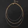 Gros plan sur collier doré multi-rangs avec mailles Figaro et boules sur fond noir - Triple Perle Figaro Dorée (HS1838-14)