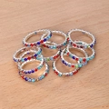 Vista macro de anillos elásticos con strass de colores y engaste de plata sobre madera - Estilo Multicolor (HS1880-5)