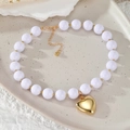 Detalle de collar de perlas multicapa con colgante de corazón dorado sobre fondo estético - Estilo Corazón Cuentas Dulce