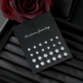 Set of 12 pairs of silver star-shaped stud earrings with clear crystals on a black card - Star Style (HS1924-4)
