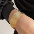 Set of stacked thin gold circular rings creating a wide cuff bracelet on wrist - Multi-layer Ultra-fine Metal Ring Style (HS1974-5)