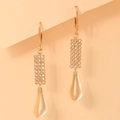 Close-up of gold plated drop earrings with micro-set cubic zirconia on orange background - Rectangle Grid Pave Matte Water Drop Style (EH098)