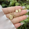 Detail of 18K gold plated cross necklace and medal earrings set held in hand - Set 1