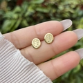 Dettaglio di orecchini a medaglione San Benito placcati in oro 18K tenuti in mano - Orecchini a Bottone Stile 1