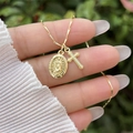 Close-up of 18K gold plated Virgin Mary and cross double pendant necklace on a hand - Necklace 2