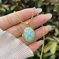 Detailed view of 18K gold-plated oval locket necklace with light blue enamel and floral motif - 18K Gold / Light Blue