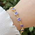 18k gold plated copper bracelet featuring purple cubic zirconia square gems on a wrist - Purple