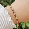 Detailed view of 18k gold plated bracelet with oval orange zircons on a woman's wrist - Orange Red (8)