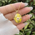 Close-up of a 18K gold-plated oval locket necklace featuring yellow enamel and floral details - 18K Gold / Yellow