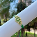 Detailed macro view of green woven bracelet featuring a gold Saint Jude medal pendant - Green