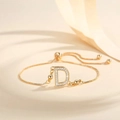 Macro shot of gold-plated bolo bracelet with zircon-encrusted letter D and adjustable chain - Letter D