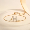 Close-up of a gold-plated adjustable bracelet with a zircon-encrusted letter H pendant - Letter H