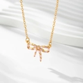 Detailed view of gold bow necklace featuring pink baguette crystals and elegant tassels - Gold / Pink Zirconia