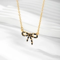 Detailed close-up of a gold-plated bow necklace featuring black zircon pendant stones - Gold / Black Zirconia