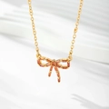 Detailed view of gold-plated bow pendant featuring amber zircon stones on white background - Gold / Red Zirconia