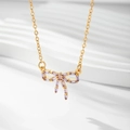 Détail du collier plaqué or avec pendentif nœud en zircon lavande sur fond blanc - Or / Zirconia Bleu